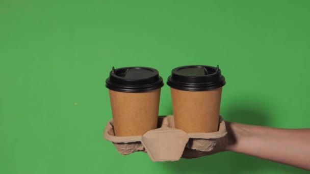 在绿色背景的特写下 一个女人的手拿着一个纸杯 咖啡放在架子上 咖啡或茶去 人们相互递给对方一杯咖啡 送咖啡 — 图库视频影像