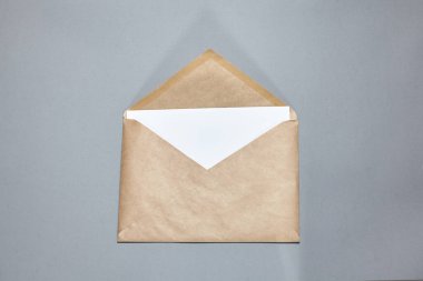 Gri arka planda kahverengi bir zarf. El işi zarfı, gri masanın üzerinde bir dal. Davetiye kartı modeli. Düz konum, üst görünüm, kopyalama alanı, alaycı