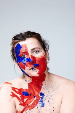 Yüzü boyalı bir kadın portresi. Yaratıcı makyaj ve parlak stil. Yüzü renkli bir kız. Sanat güzelliği. Yüzünde renkli boya olan bir kız.. 