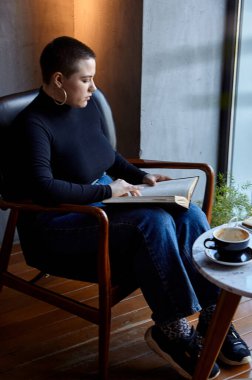 Genç bir kız bir kafede oturmuş kitap okuyor. Eğitim ve uzak çalışma kavramı 