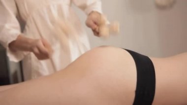 Kadın masör, kadın kalçasına anti-selülit masajı yapıyor. Maderoterapi tedavisi. Spa tedavileri, sağlık, güzellik, diyet. Müşterinin kalçalarının ve masörün ellerinin yakın çekim görüntüsü.