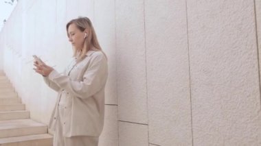 Genç bir kadın bir video çağrısına cevap veriyor. Kablosuz kulaklık takan sarı saçlı bir kadın merdivenlerden iniyor ve video bağlantısıyla konuşuyor. 