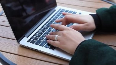 Eğitim ve uzaktan çalışma kavramı. Gözlüklü, kısa saçlı ve burun piercingli genç bir kadın bir kafede oturuyor ve bir dizüstü bilgisayar üzerinde çalışıyor. Serbest çalışma ve uzak çalışma veya eğitim kavramı.