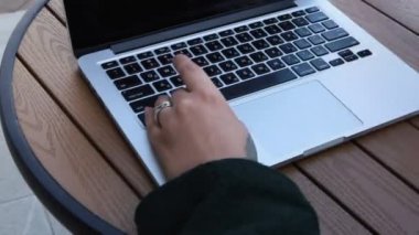 Eğitim ve uzaktan çalışma kavramı. Gözlüklü, kısa saçlı ve burun piercingli genç bir kadın bir kafede oturuyor ve bir dizüstü bilgisayar üzerinde çalışıyor. Serbest çalışma ve uzak çalışma veya eğitim kavramı.