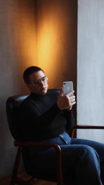 Eğitim ve uzaktan çalışma kavramı. Gözlüklü, kısa saçlı ve burun piercingli genç bir kadın bir kafede oturuyor ve bir dizüstü bilgisayar üzerinde çalışıyor. Serbest çalışma ve uzak çalışma veya eğitim kavramı.