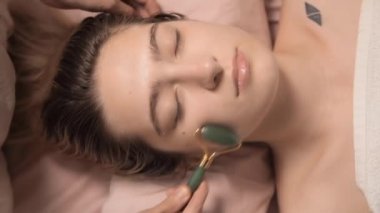 Genç ve güzel bir kadın sağlık merkezinde Gua Sha masajı yaptırıyor. Masör, kaplıca salonundaki genç ve güzel bir kızın kafasına masaj yapıyor. Makroyu kapat. 