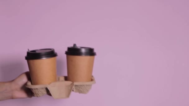 手拿着彩色背景的杯子 茶或咖啡去 带黑色盖子的棕色纸杯 — 图库视频影像
