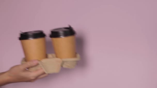色の背景にカップを保持手 紅茶やコーヒーを移動します 黒蓋の茶色い紙コップ — ストック動画