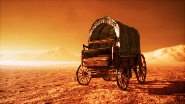 Chariot rétro recouvert de toile dans le désert au coucher du soleil — Video