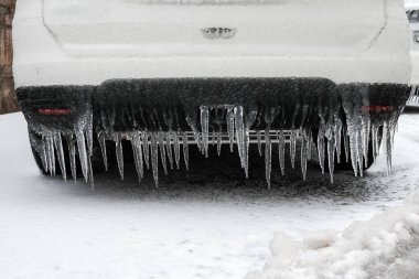 Ice-covered car bumper with icicles close up, vehicle parking safety after freezing rain in Europe. clipart