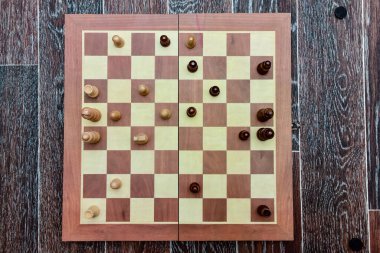 Bir satranç oyunu sırasında beyaz ve siyah satranç taşları güvertede durur. en üstteki görünüm.