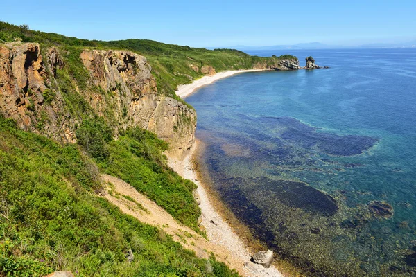Dağlar ve mavi gökyüzü ile deniz manzarası. Dağlarda yeşil bitki örtüsü, kumlu sahil ve inanılmaz deniz..