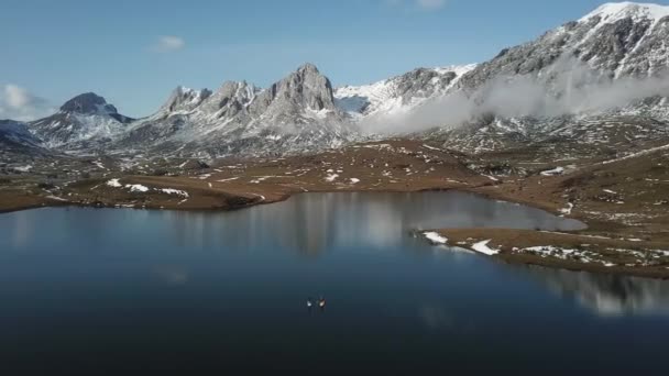 Paddle surf su un lago di montagna innevato. Vista drone — Video Stock