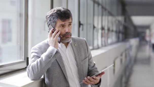 Een man praat aan de telefoon in een gang. — Stockvideo