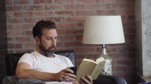 Un homme lisant un livre à la maison — Video