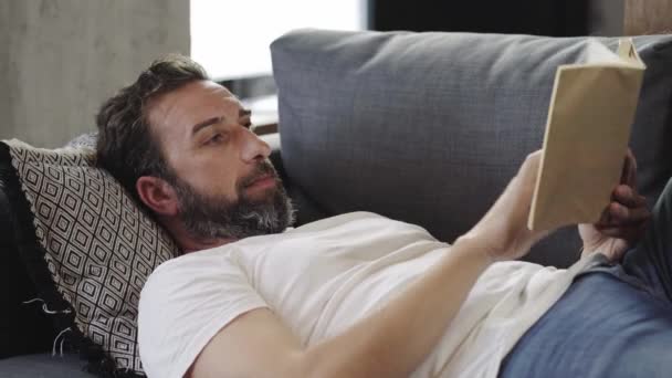 Мужчина, читающий книгу дома — стоковое видео