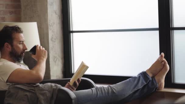 Egy férfi, aki otthon könyvet olvas. — Stock videók