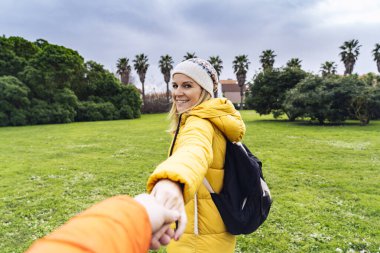 Bir parkın arka planında el ele tutuşan kadın