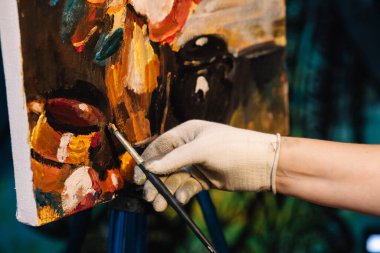 Ressam, elinde paletle yağlı boya fırçası resmi çiziyor..