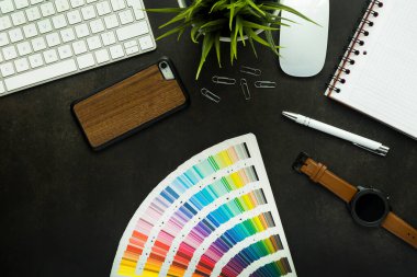 Siyah masa ve klavyeli grafik tasarımcı çalışma alanı, bitki, fare, not defteri, akıllı telefon ve kalem - üst görünüm