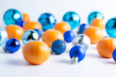 Mandalina Noel topları mavi tonlarda beyaz arka planda yatar. Bokeh efektli Noel arkaplanı.