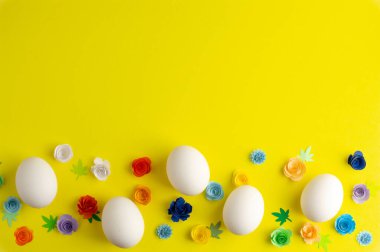 Paskalya yumurtaları ve kağıttan çiçekler sarı arka planda, yazı yazmak için yer var. Paskalya arkaplanı.