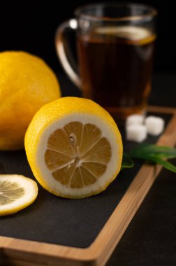 Limon dilimleme tahtasındaki bulanık görüntü, bir bardak limonlu çay, küp şeker. Fotoğraf: Bokeh etkisi..