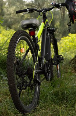 Gidonunda kask olan bir bisiklet çayırın bulanık arka planında duruyor. Fotoğraf: Bokeh efektli..