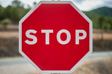 Mavi gökyüzüne karşı kırmızı zemin ve otoyoldaki bazı ağaçlara dayalı sekizgen dur işaretinin ayrıntıları