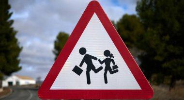 Kırmızı kenarı ve beyaz arkaplanı olan ve çocukların okula geçişini temsil eden üçgen trafik işaretinin ayrıntıları.