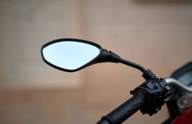 Bulanık bir arka planda kırmızı bir motosikletin modern bir dikiz aynası.