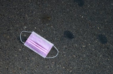 Kirli ve kullanılmış pembe bir maskenin ayrıntıları. Sokakta yatan kovid-19 koruması için.