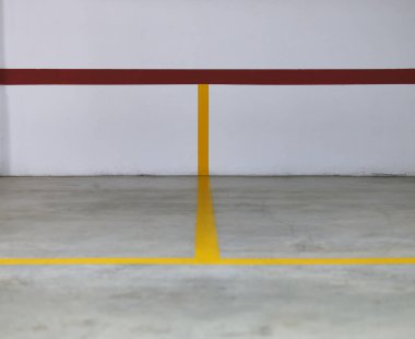 Duvardaki sarı ve kırmızı çizgilerin ayrıntıları ve park alanlarını sınırlayan beton zemin.