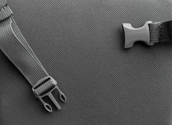 detail of a loose strap on the back of a gray backpack