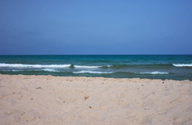 Yeşil deniz ve mavi gökyüzü olan beyaz kumlu bir plajın ayrıntıları