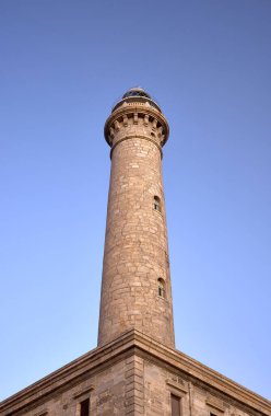 Mavi gökyüzü olan taştan bir deniz feneri kulesinin detayları