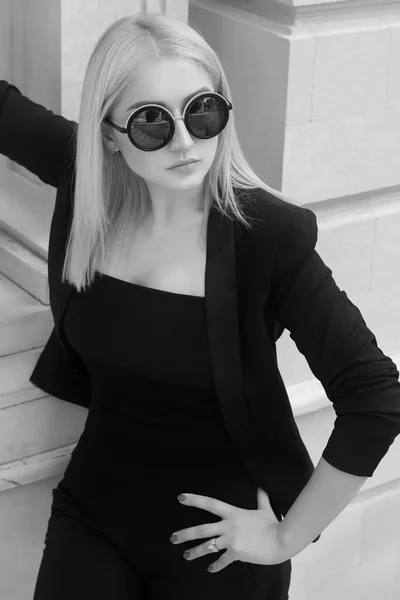 Young fashion business woman in sunglasses walking on the city street.