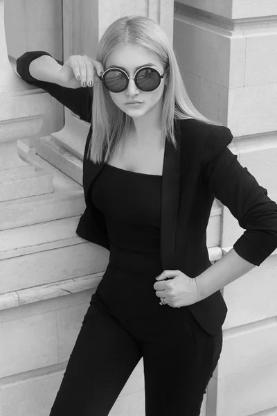 Young fashion business woman in sunglasses walking on the city street.