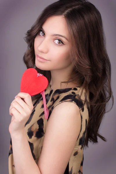 Love and valentines day woman holding heart smiling cute and adorable. Valentine's Day. Portrait of Beautiful gorgeous smiling woman with glamour bright makeup and red heart in hand — Stock Photo, Image