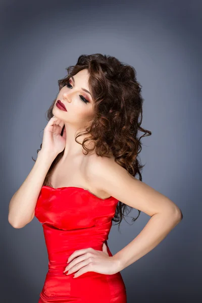 Hermosa morena con hermoso pelo rizado. Foto de moda de una hermosa mujer joven en vestido rojo elegante . — Foto de Stock