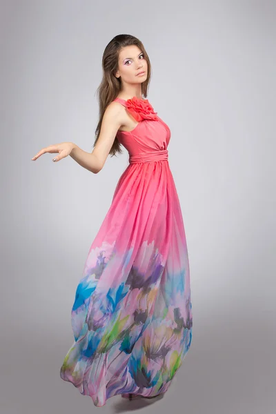 Красивая девушка в воздушном платье. Красивая брюнетка в розовом платье изолированы на сером фоне — стоковое фото
