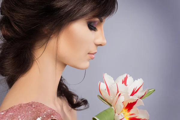 Primavera belleza modelo estudio de rodaje. Retrato de una joven sonriente con flores tulipanes naranjas sobre fondo blanco. Maquillaje fresco de moda. Los labios sensuales. Piel perfecta. Ternura. Estilo romántico —  Fotos de Stock