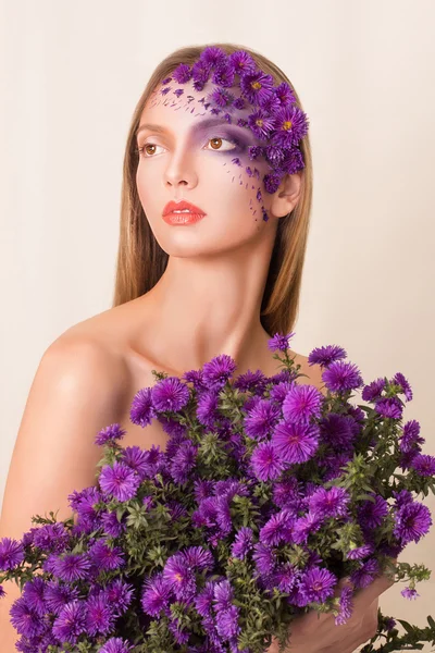 Modèle de mode avec une grande coiffure et des fleurs dans son visage . — Photo