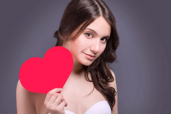 Porträt einer wunderschönen lächelnden Frau mit Glamour hellem Make-up und rotem Herz in der Hand. Valentinstag. schöne lächelnde Frau mit einem Geschenk in Form von zwei Herzen in seinen Händen. — Stockfoto