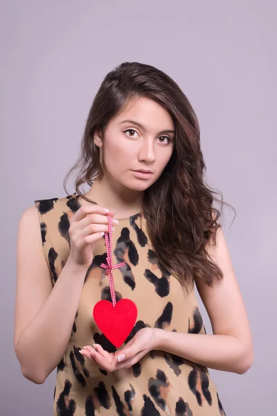 Portrait of Beautiful gorgeous smiling woman with glamour bright makeup and red heart in hand. Valentine's Day. Beautiful smiling woman with a gift in the form of two heart in his hands. — Stock Photo, Image