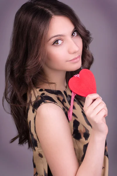 Portrait de Belle femme souriante magnifique avec un maquillage éclatant glamour et coeur rouge à la main. Saint-Valentin. Belle femme souriante avec un cadeau en forme de deux cœurs dans ses mains . — Photo