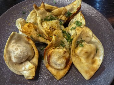 Et ile doldurulmuş kızarmış hamur tatlısı, doğranmış dereotu serpiştirilmiş.,..