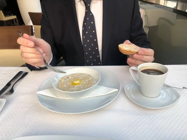 Businessman eating breakfast: a cup of espresso coffee and oatmeal, the concept of proper nutrition. Healthy Breakfast Organic Oatmeal