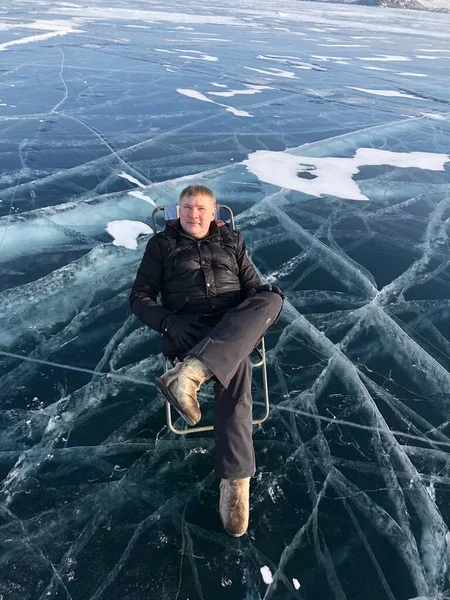 Turista ül a felszínen a repedések a fagyott Bajkál-tó a téli szezonban Szibériában, Oroszországban. A Bajkál-tó a világ legnagyobb édesvízi tava és a világ legmélyebb tava.. — Stock Fotó