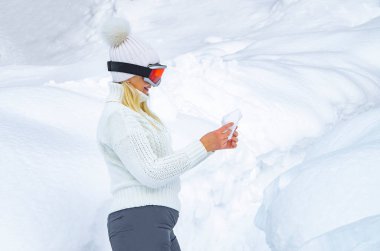 Beyazlı mutlu kadın, karlı ormanda kış tatilinin tadını çıkarıyor.